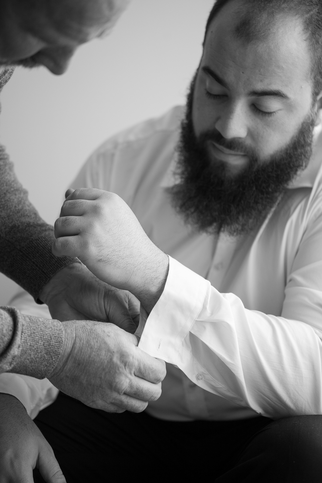 groom having his cufflink put on