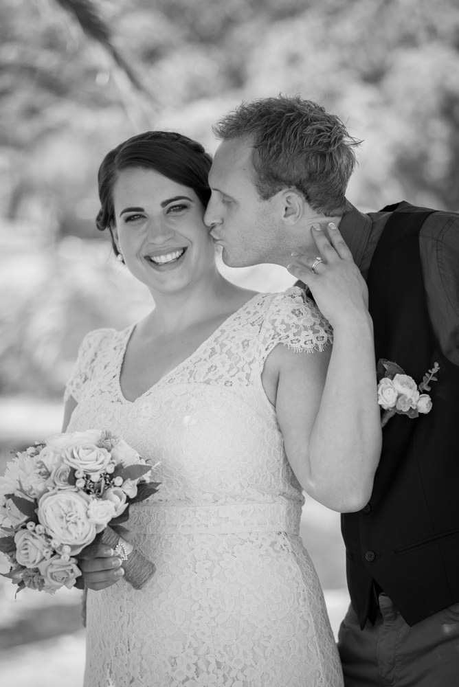 Black and white photo of groom kissing the bride on the cheek