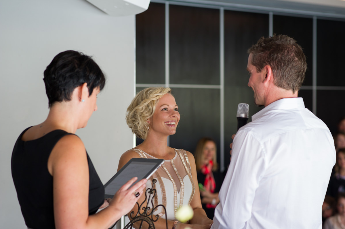 Bride and groom and celebrant exchange vows smiling