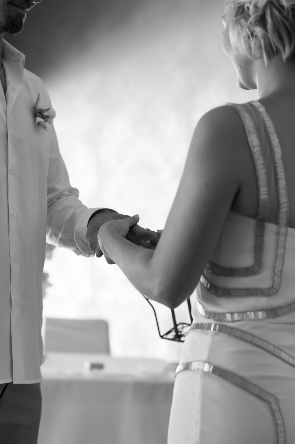 Black and white photo of bride putting ring on groom's finger