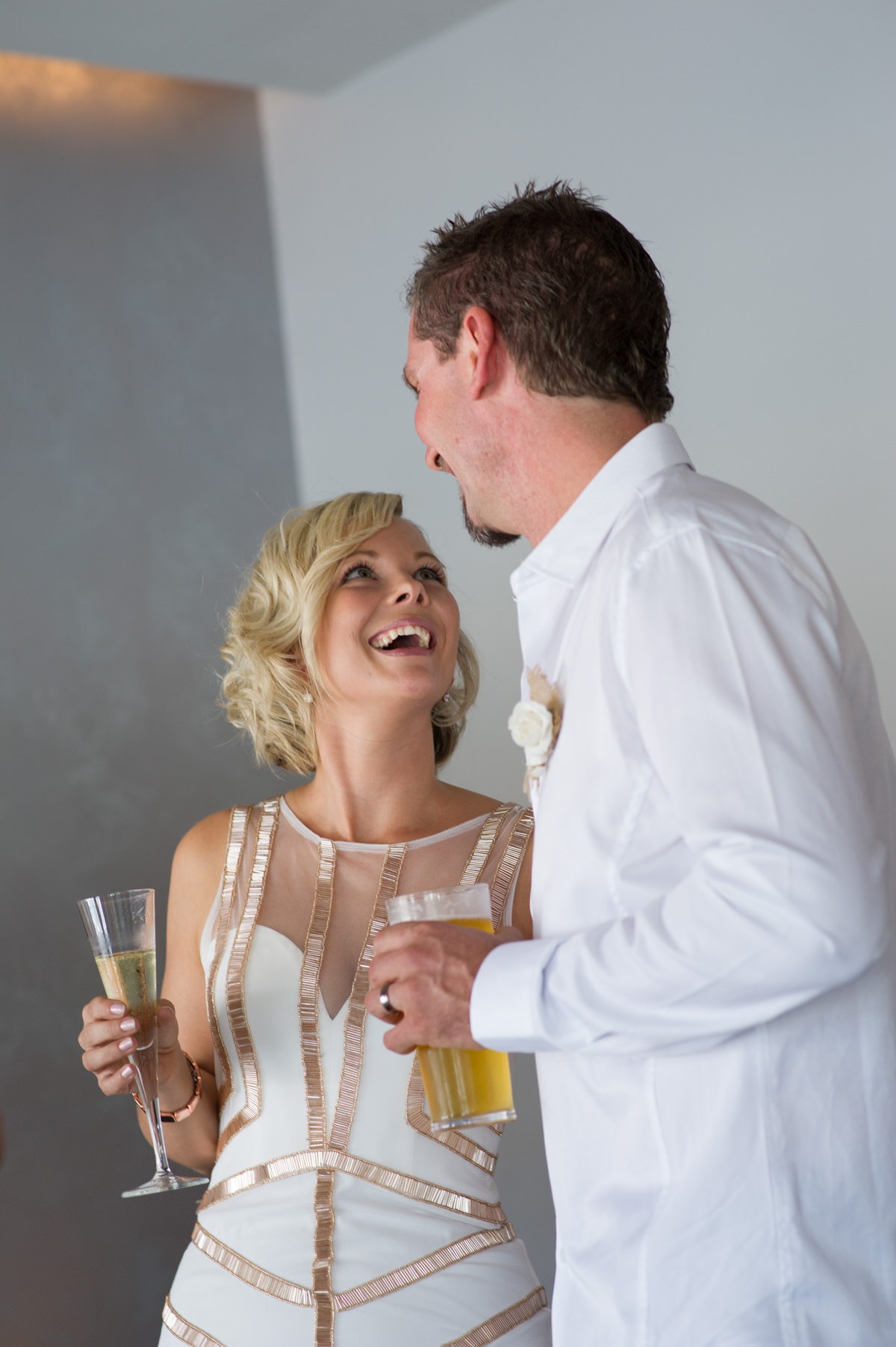 Bride and groom laughing at each other during toast