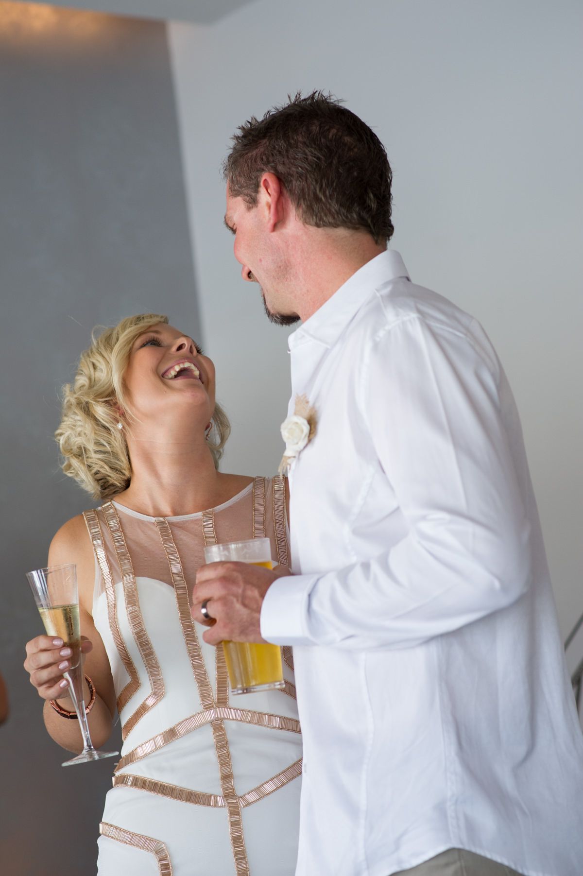 Bride and groom share a joke with a drink in hand