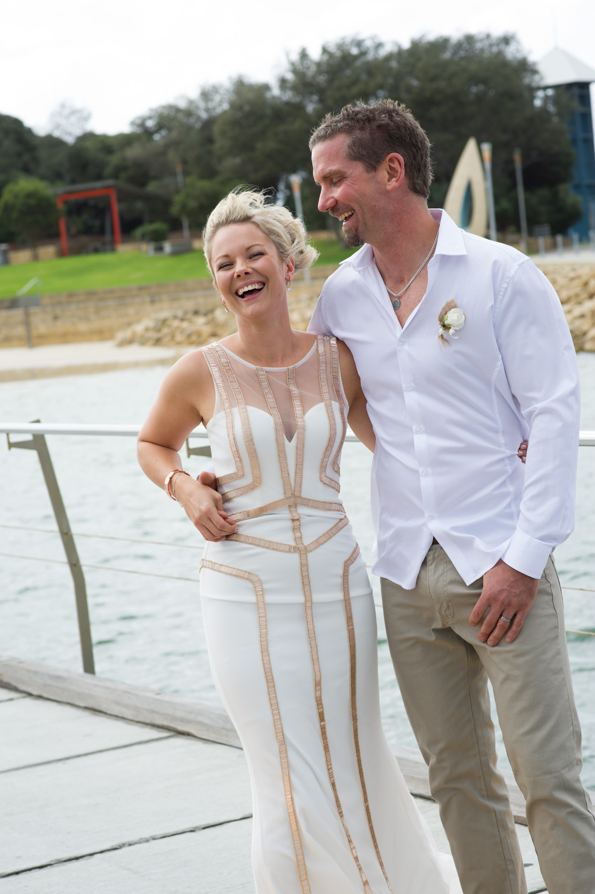 Bride and groom laughing outside on a windy day