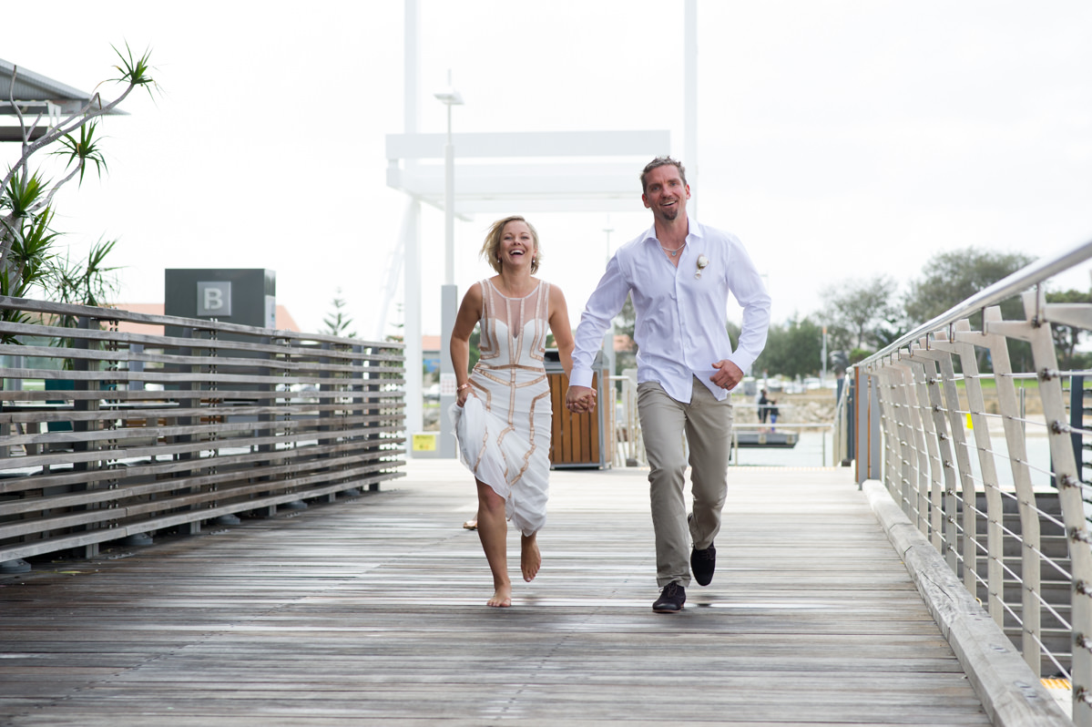 Bride and groom skipping at The breakwater bridge