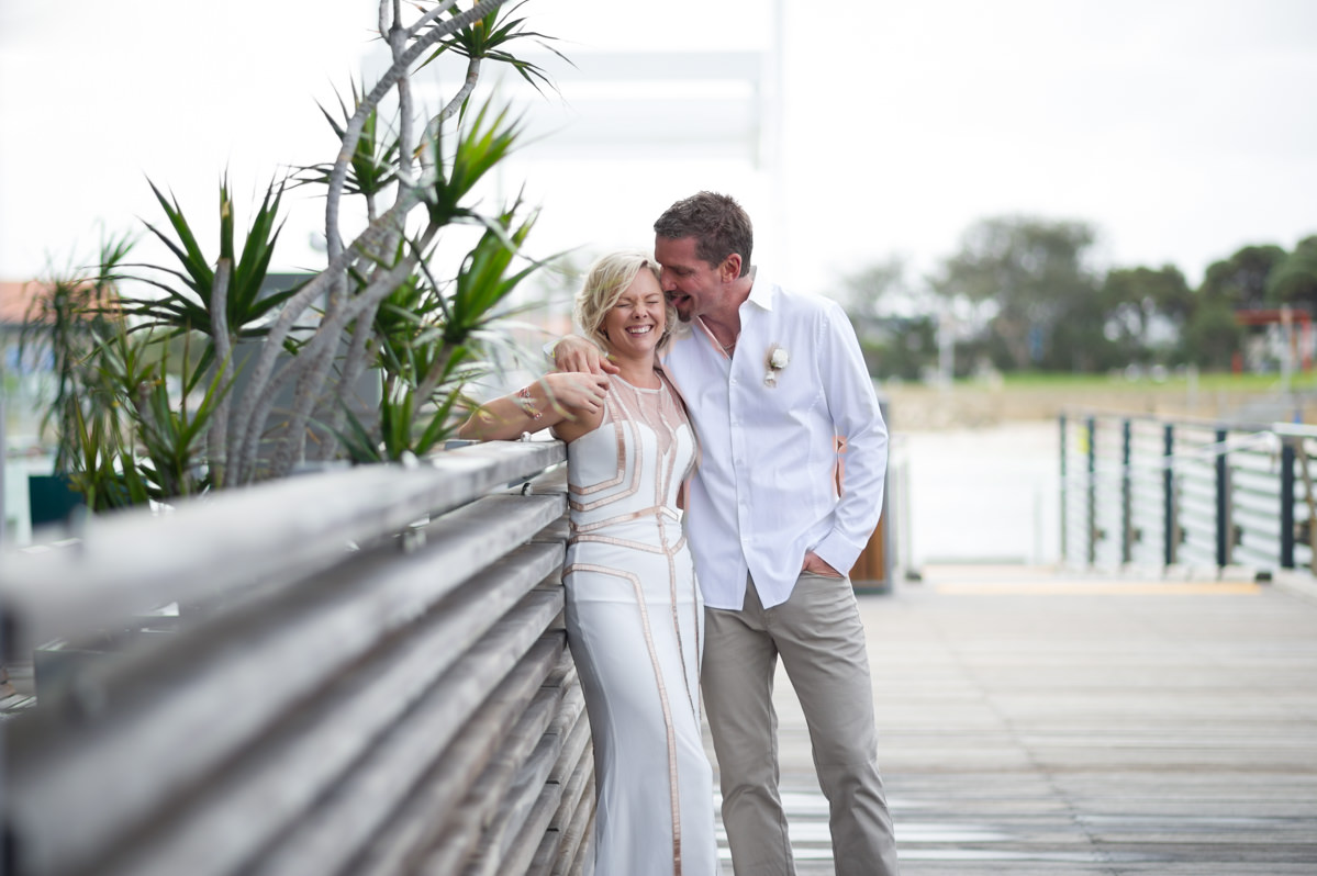 Groom puts his tongue in bride's ear while she laughs