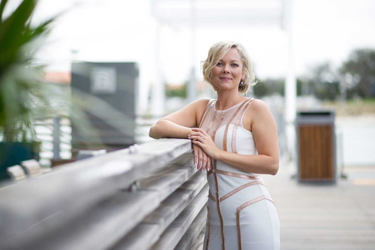 Bride leaning against the fence at The Breakwater