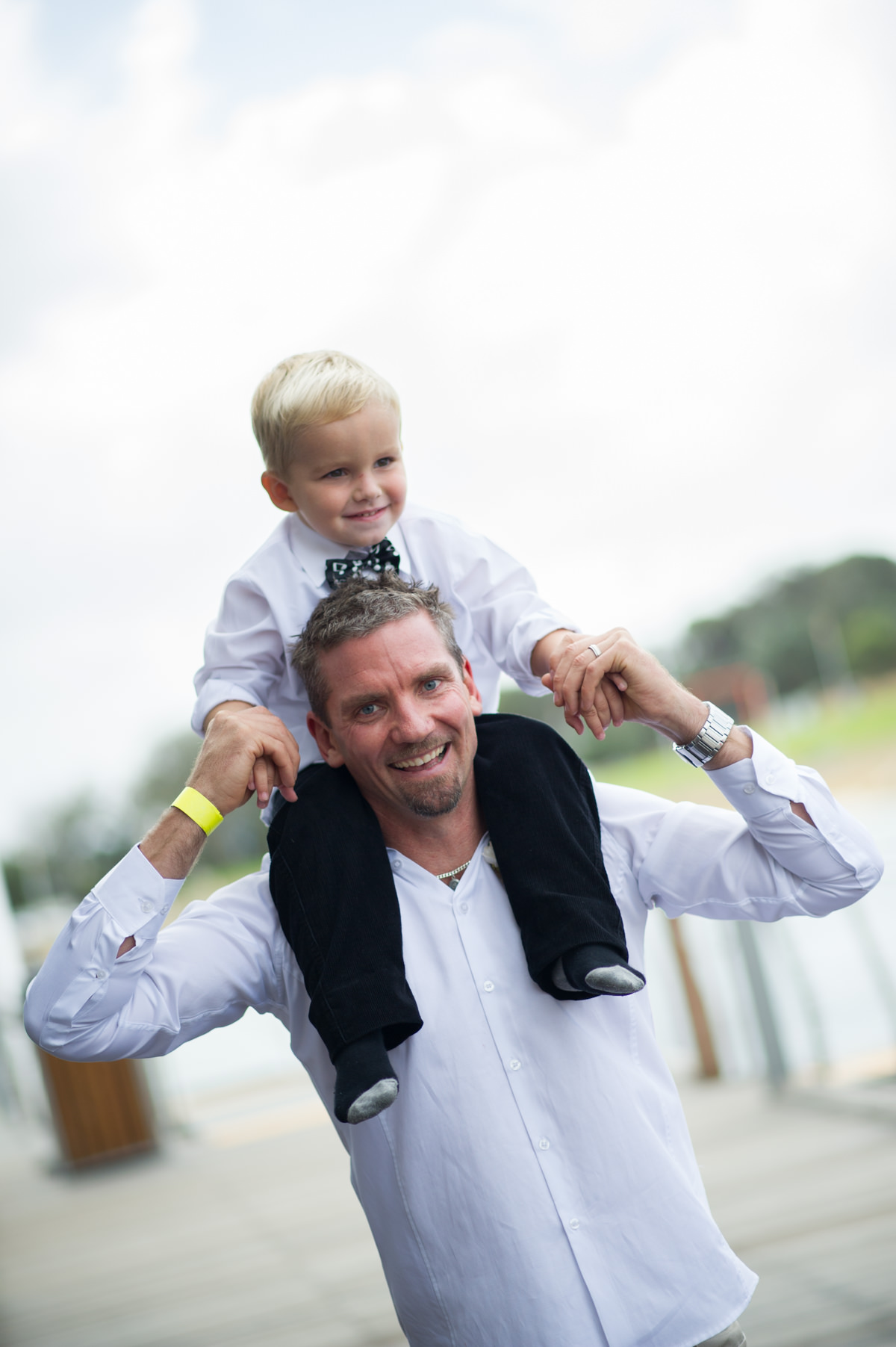 Little boy sits on groom's shoulders