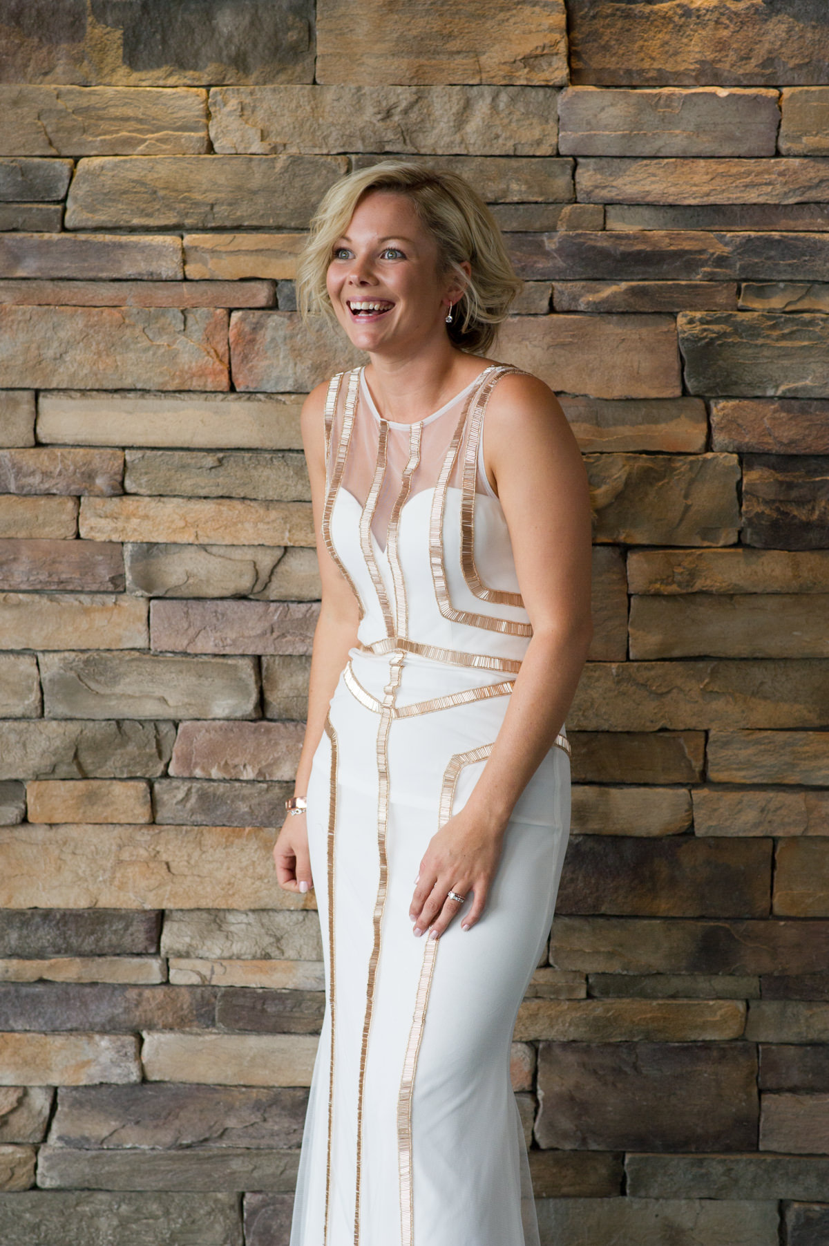 Bride leaning against a brick decorative wall at The Breakwater