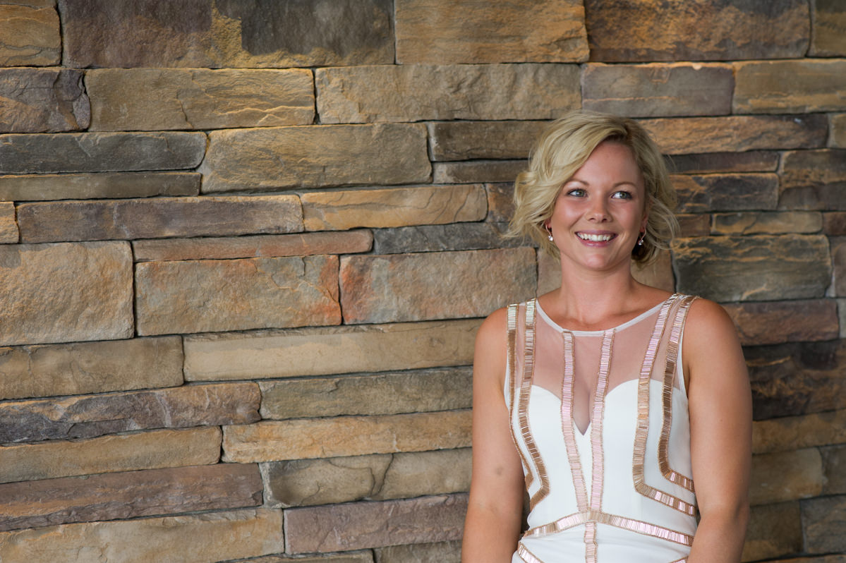 Bride leaning against a brick decorative wall at The Breakwater