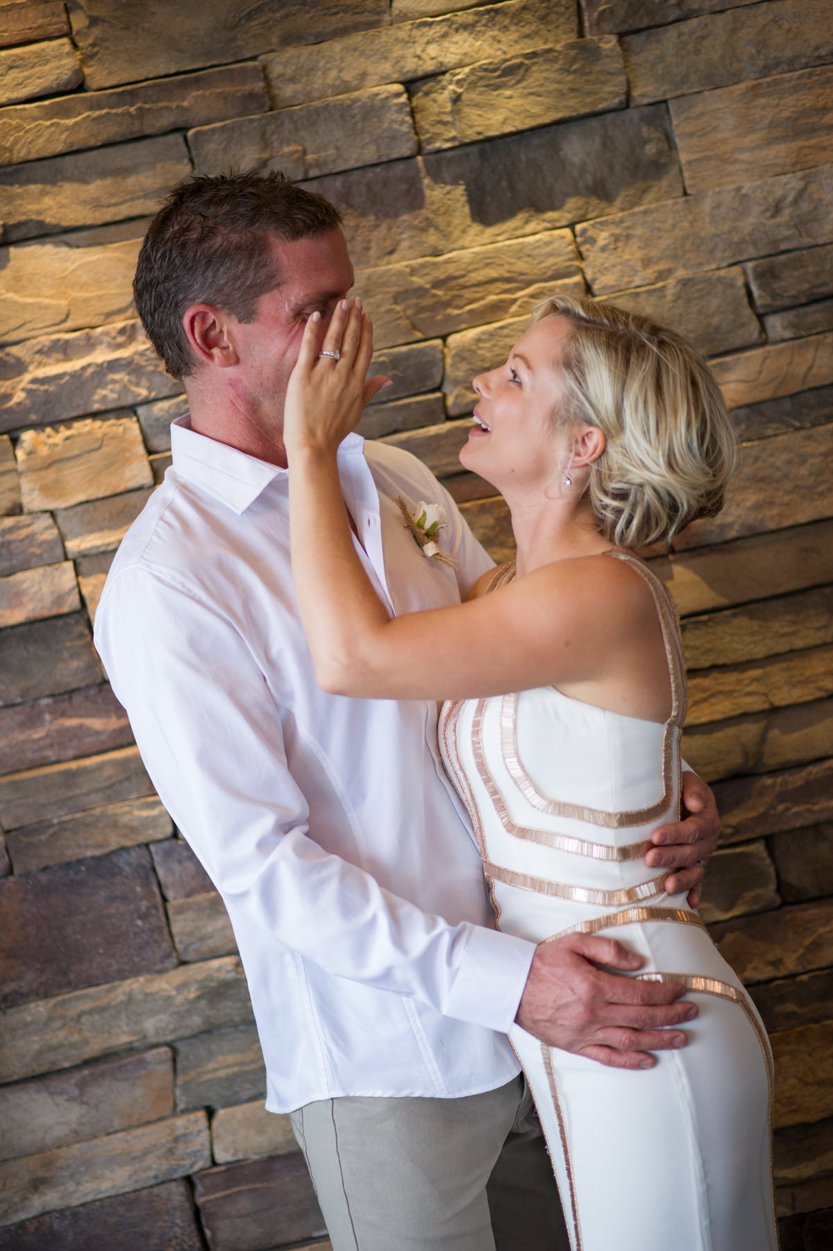 Bride and groom standing against brick wall at The Breakwater